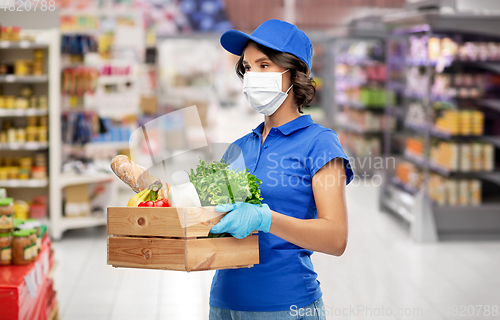 Image of delivery girl in mask with food in box at store