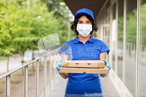 Image of delivery woman in mask with pizza boxes outdoors