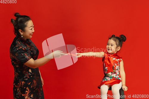 Image of Happy Chinese New Year. Asian mother and daughter portrait isolated on red background