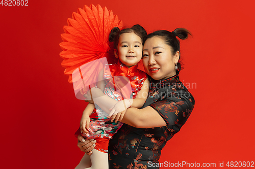 Image of Happy Chinese New Year. Asian mother and daughter portrait isolated on red background