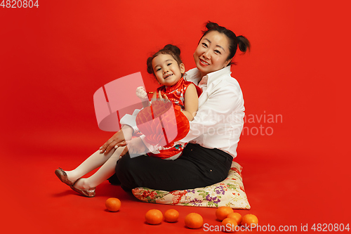 Image of Happy Chinese New Year. Asian mother and daughter portrait isolated on red background