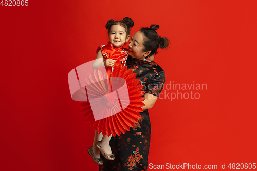 Image of Happy Chinese New Year. Asian mother and daughter portrait isolated on red background