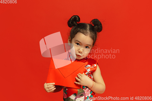 Image of Happy Chinese New Year. Asian little girl portrait isolated on red background