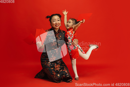 Image of Happy Chinese New Year. Asian mother and daughter portrait isolated on red background