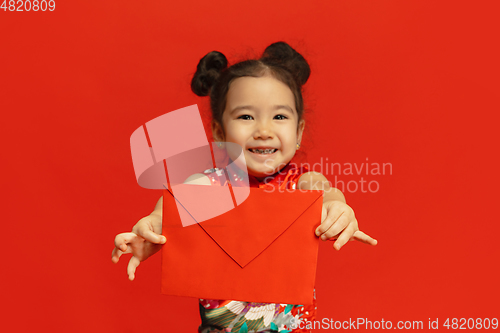 Image of Happy Chinese New Year. Asian little girl portrait isolated on red background