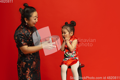 Image of Happy Chinese New Year. Asian mother and daughter portrait isolated on red background