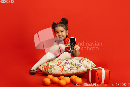 Image of Happy Chinese New Year. Asian little girl portrait isolated on red background