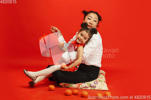 Image of Happy Chinese New Year. Asian mother and daughter portrait isolated on red background