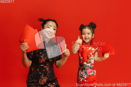 Image of Happy Chinese New Year. Asian mother and daughter portrait isolated on red background