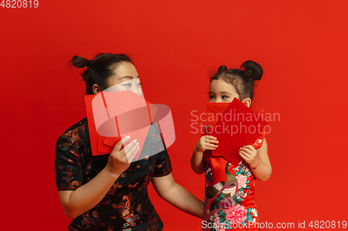 Image of Happy Chinese New Year. Asian mother and daughter portrait isolated on red background