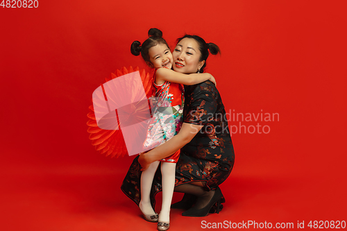 Image of Happy Chinese New Year. Asian mother and daughter portrait isolated on red background