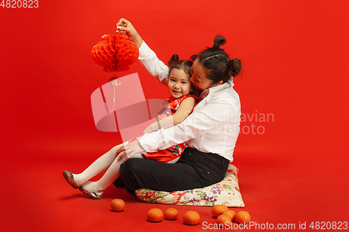 Image of Happy Chinese New Year. Asian mother and daughter portrait isolated on red background