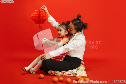 Image of Happy Chinese New Year. Asian mother and daughter portrait isolated on red background