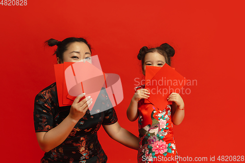 Image of Happy Chinese New Year. Asian mother and daughter portrait isolated on red background