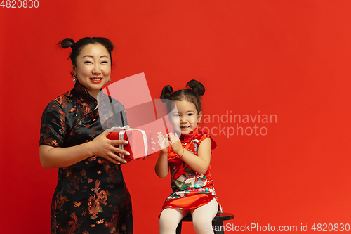 Image of Happy Chinese New Year. Asian mother and daughter portrait isolated on red background