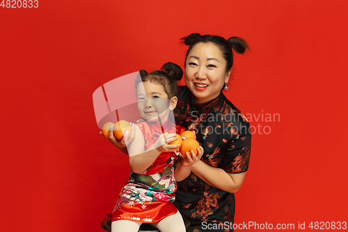 Image of Happy Chinese New Year. Asian mother and daughter portrait isolated on red background