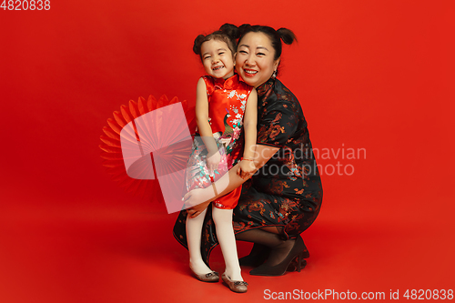 Image of Happy Chinese New Year. Asian mother and daughter portrait isolated on red background