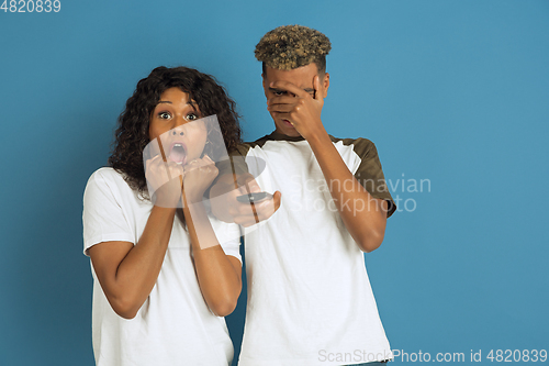 Image of Young emotional african-american man and woman on blue background