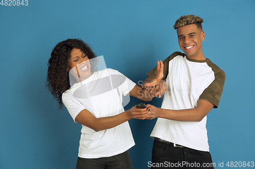 Image of Young emotional african-american man and woman on blue background