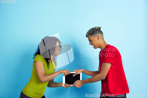 Image of Young emotional african-american man and woman on blue background