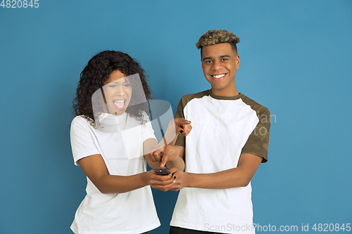 Image of Young emotional african-american man and woman on blue background