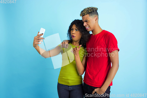 Image of Young emotional african-american man and woman on blue background