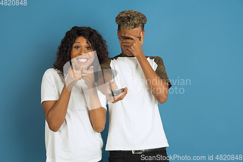 Image of Young emotional african-american man and woman on blue background