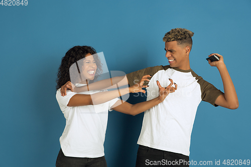 Image of Young emotional african-american man and woman on blue background