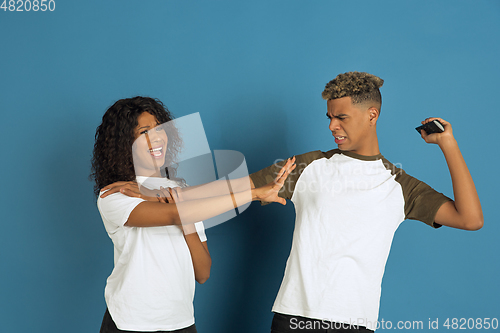 Image of Young emotional african-american man and woman on blue background