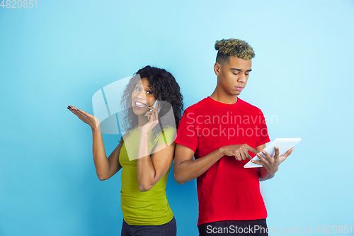 Image of Young emotional african-american man and woman on blue background