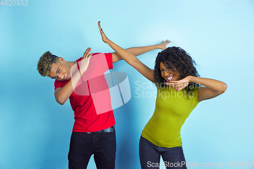 Image of Young emotional african-american man and woman on blue background