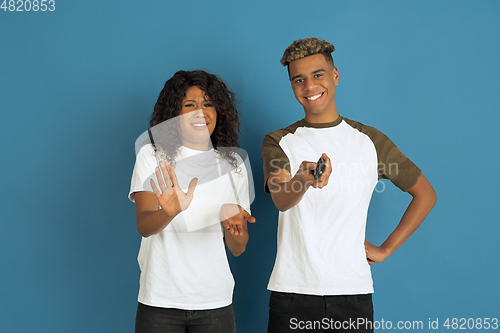 Image of Young emotional african-american man and woman on blue background