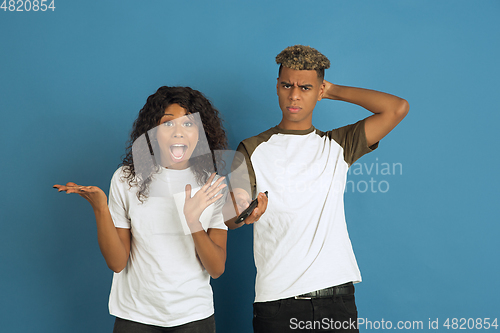 Image of Young emotional african-american man and woman on blue background