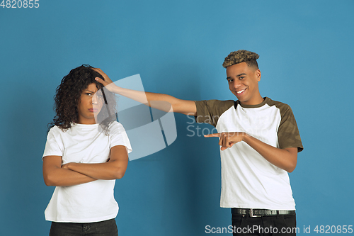 Image of Young emotional african-american man and woman on blue background