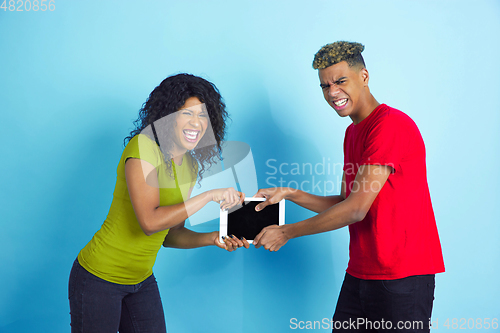 Image of Young emotional african-american man and woman on blue background