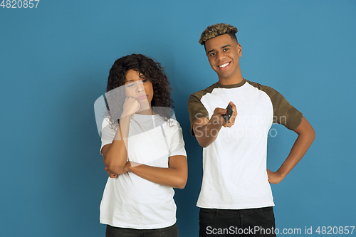 Image of Young emotional african-american man and woman on blue background