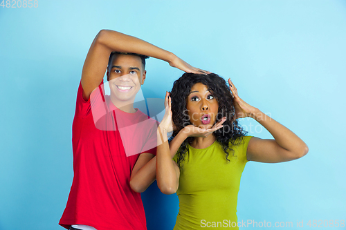 Image of Young emotional african-american man and woman on blue background