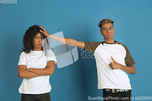 Image of Young emotional african-american man and woman on blue background