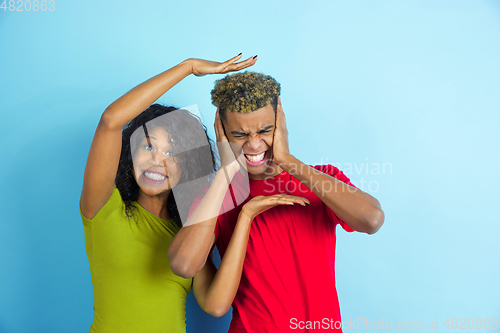 Image of Young emotional african-american man and woman on blue background