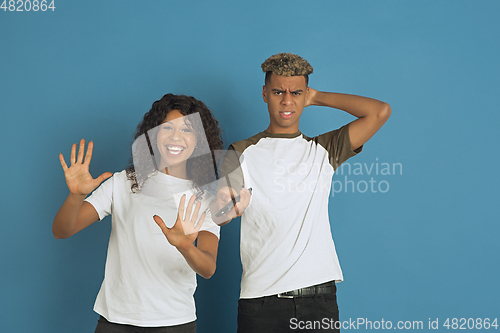 Image of Young emotional african-american man and woman on blue background