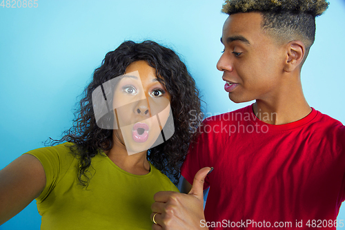 Image of Young emotional african-american man and woman on blue background