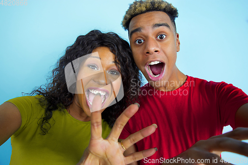 Image of Young emotional african-american man and woman on blue background