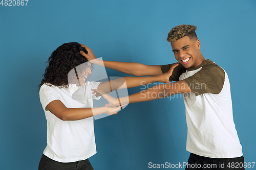 Image of Young emotional african-american man and woman on blue background