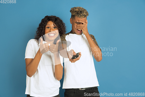 Image of Young emotional african-american man and woman on blue background