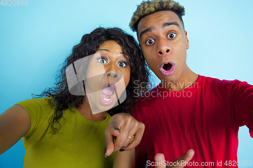 Image of Young emotional african-american man and woman on blue background