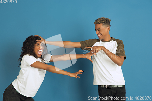 Image of Young emotional african-american man and woman on blue background