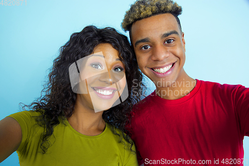 Image of Young emotional african-american man and woman on blue background