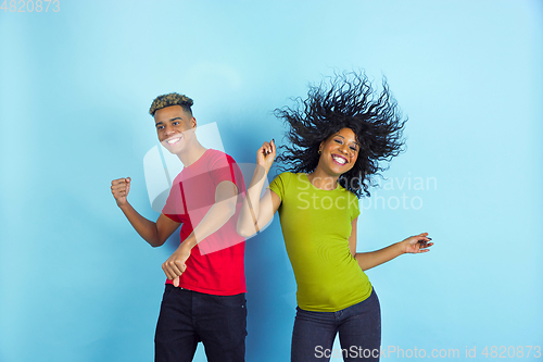 Image of Young emotional african-american man and woman on blue background