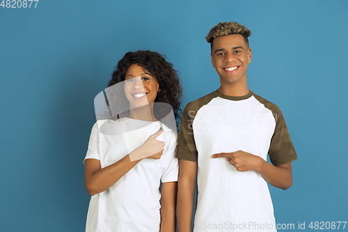 Image of Young emotional african-american man and woman on blue background