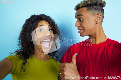 Image of Young emotional african-american man and woman on blue background